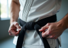 Pratiquant de Jiu Jitsu nouant une ceinture noire dans un dojo lumineux
